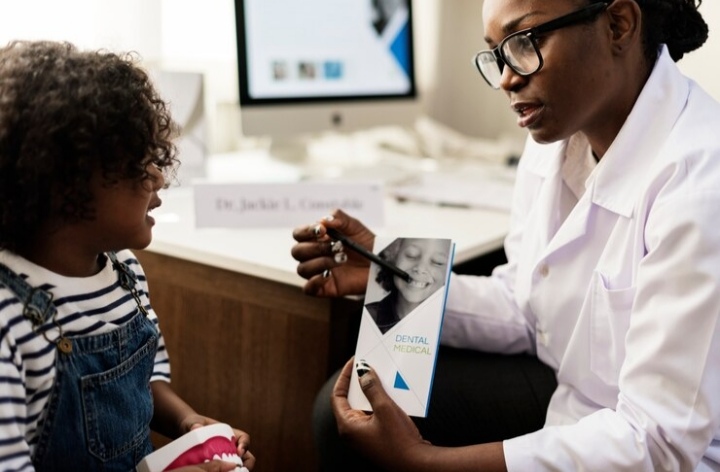 Optometrist conducting an eye exam on a young child using an eye chart with colorful shapes.